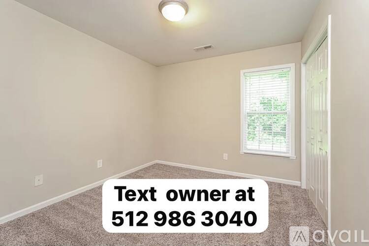 A room with a window and a carpeted floor is available for rent.