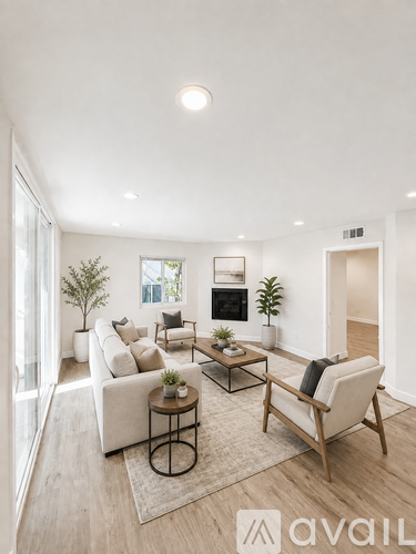 A living room with a white couch, a coffee table, and a plant.