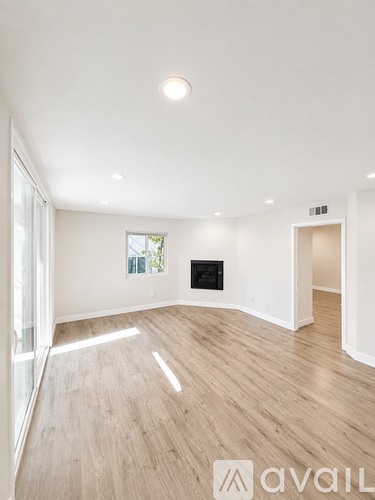 A spacious room with wooden flooring and a fireplace.
