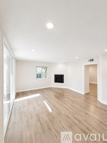 A spacious room with wooden flooring and a fireplace.