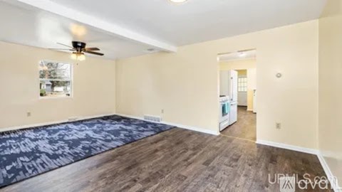 A spacious room with a ceiling fan and a rug on the floor.