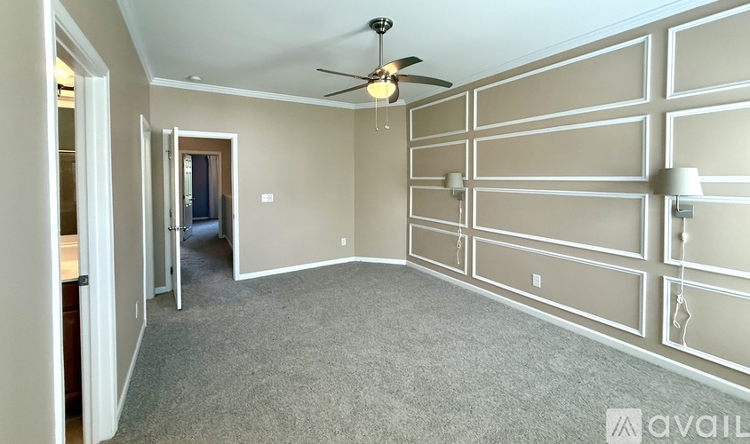 A spacious room with a ceiling fan and carpeted floor.