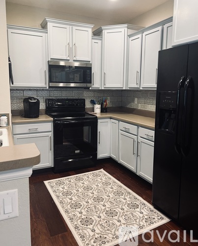 A kitchen with black appliances and white cabinets.