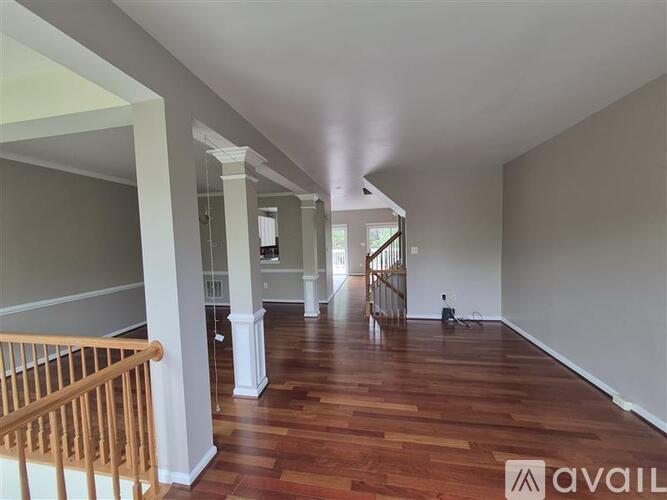 A spacious room with wooden floors and white columns.