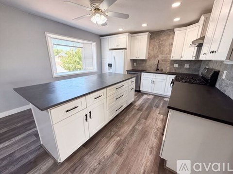 A kitchen with white cabinets and a black countertop.