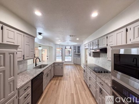 A spacious kitchen with wooden floors and granite countertops.