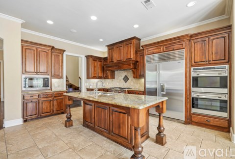 A kitchen with wooden cabinets and a marble island.