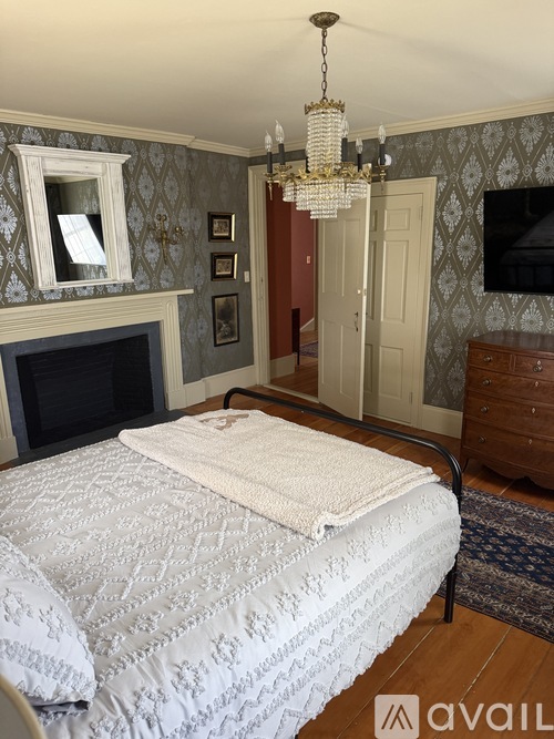 A bedroom with a large bed and a chandelier.