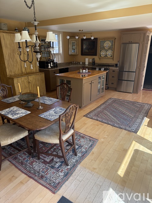 A kitchen with a table set for two with a chandelier hanging above.