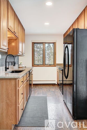 A kitchen with wooden cabinets and a black refrigerator.