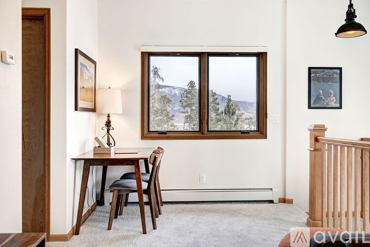 A dining room with a table and chairs and a window overlooking a mountain.