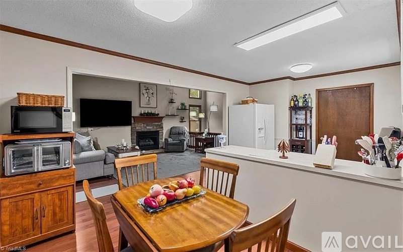 A kitchen with a table and chairs in the foreground and a refrigerator in the background.