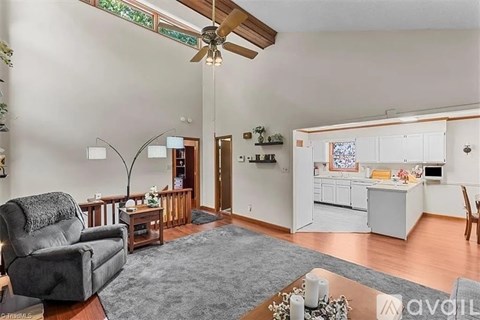 A living room with a grey rug and a black leather chair.