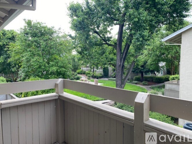 A balcony with a view of a green lawn and trees.