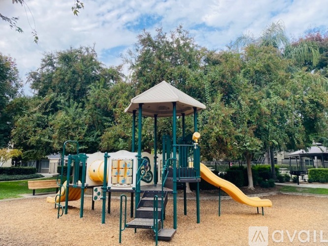 A playground with a yellow slide and a green structure.