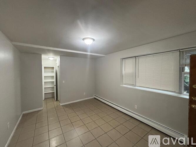 A room with tiled flooring and a window with blinds.