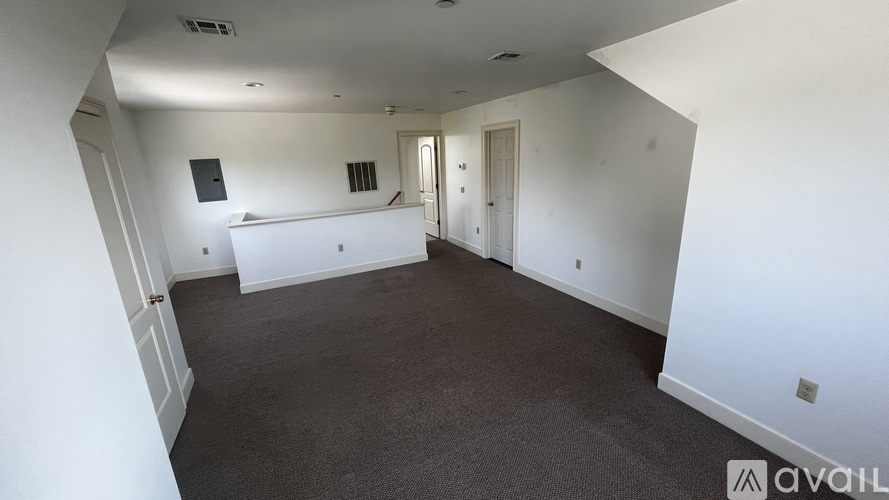 A spacious empty room with white walls and carpeted floor.