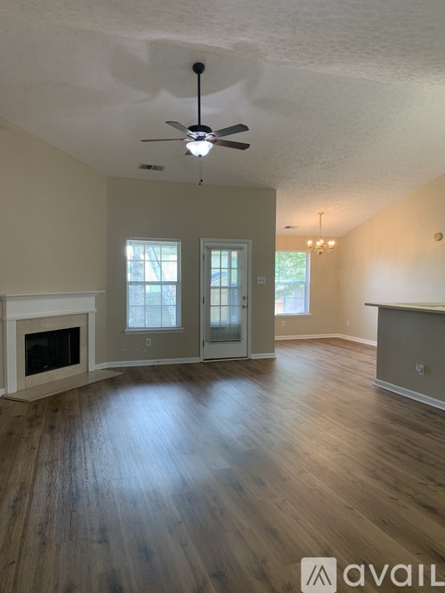 A spacious living room with wood flooring and a fireplace.