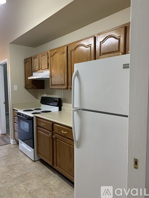A kitchen with a white refrigerator, wooden cabinets, and a black stove top oven.
