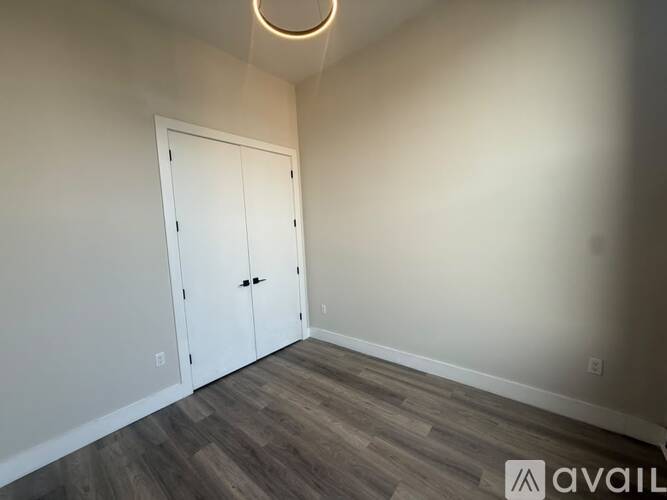 A room with a white door and wooden flooring.