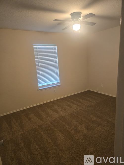 A room with a carpeted floor, a ceiling fan, and a window with blinds.