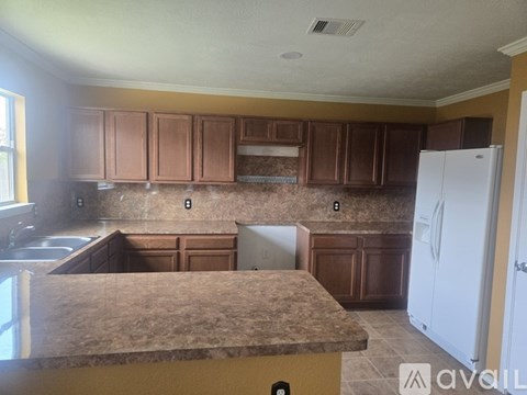 A kitchen with brown cabinets and a white refrigerator.