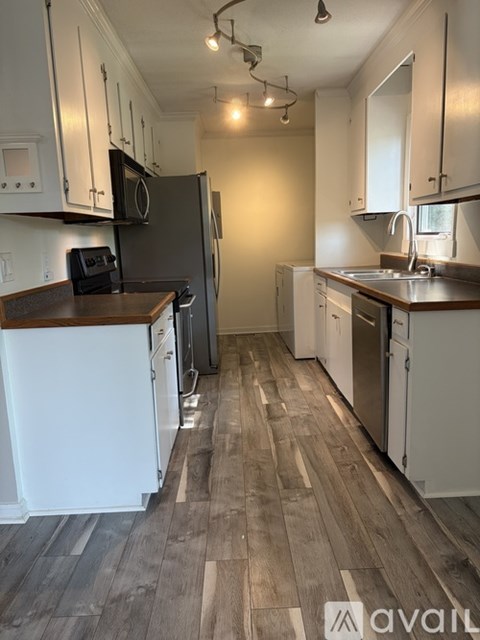 A kitchen with white cabinets and a wooden floor.