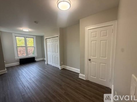 A room with a white door and a window with a view of trees.