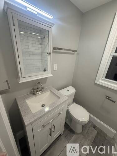 A bathroom with a toilet, sink, and mirror.