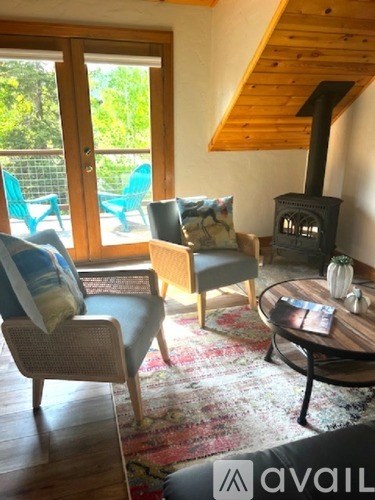 A living room with a wood stove and a table with a vase on it.