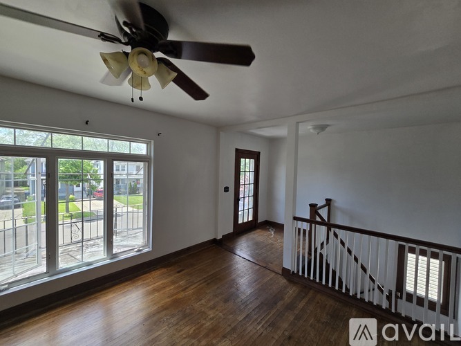A room with a ceiling fan and wooden floors.