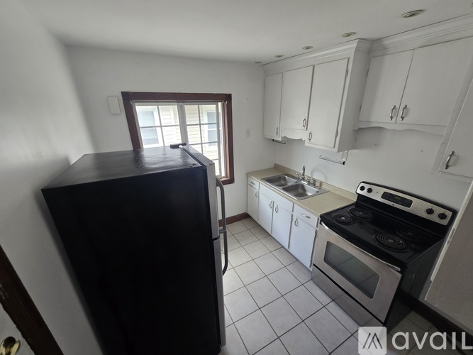 A kitchen with white cabinets and a black refrigerator.