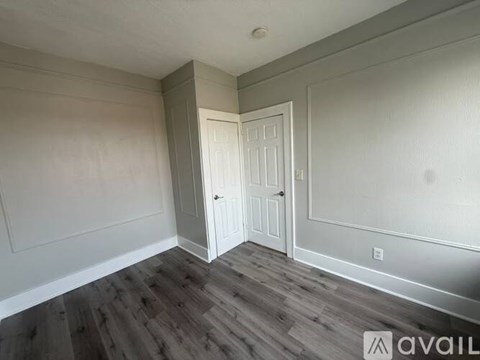 A room with a white door and wooden flooring.