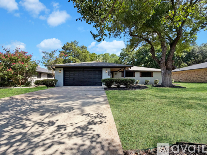 A house with a driveway and a tree in front.