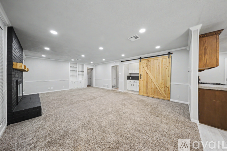 A spacious living room with a fireplace and a carpeted floor.