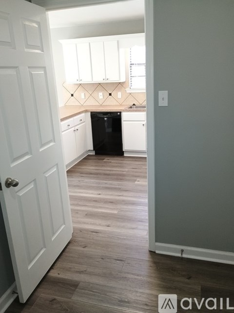 A kitchen with white cabinets and a black dishwasher.
