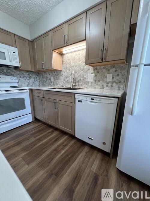 A kitchen with wooden floors and white appliances.