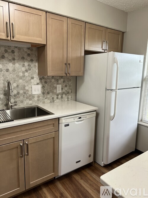A kitchen with a white fridge and wooden cabinets.