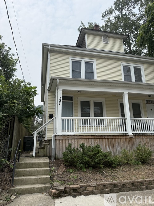 A two-story house with a front porch and stairs leading up to the front door.
