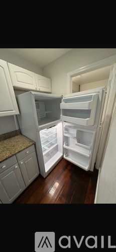 A kitchen with white cabinets and a white refrigerator with the door open.