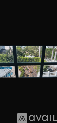 A window with a view of a pool and greenery.