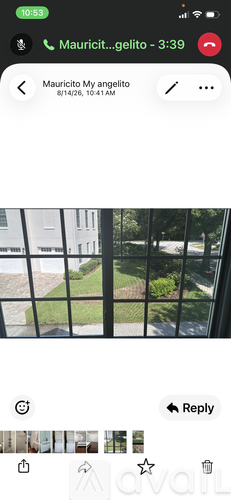 A window with a view of a green lawn and a white building.