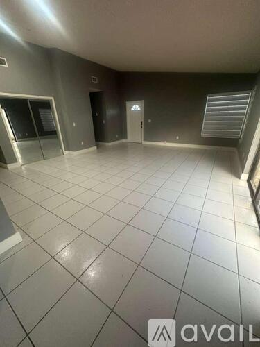 A spacious room with tiled flooring and a staircase to the right.