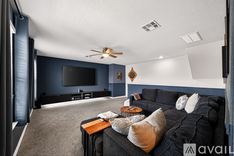 A living room with a black couch and a ceiling fan.