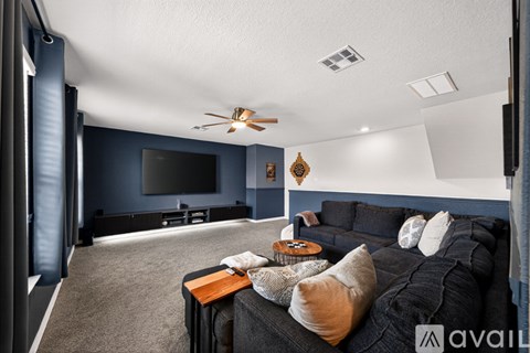 A living room with a black couch and a ceiling fan.