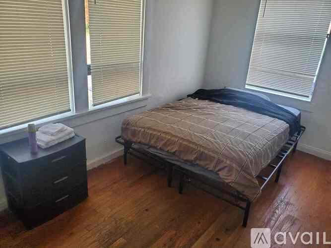 A bedroom with a bed, dresser, and window with blinds.