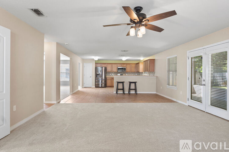 A spacious room with a ceiling fan and a bar area.