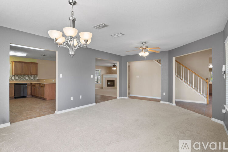 A spacious living room with a chandelier and a ceiling fan.