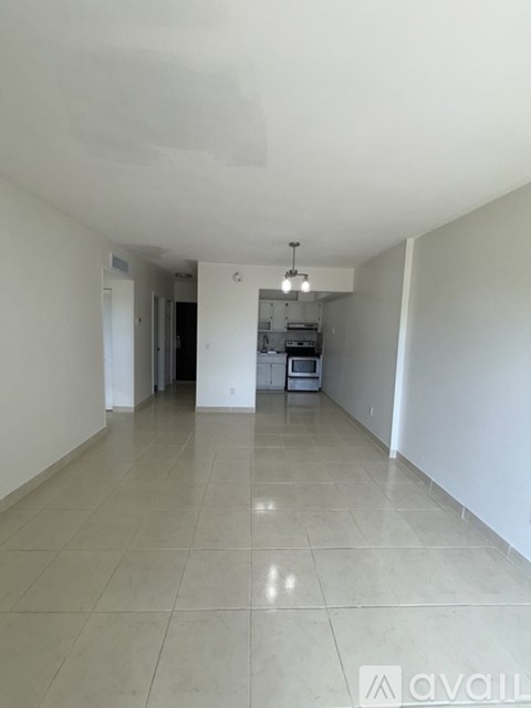 A spacious room with a kitchen area in the background.