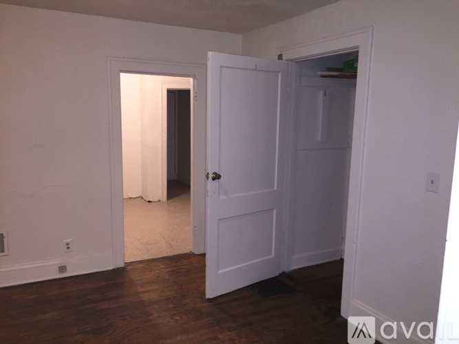 A white door is open in a room with wooden floors.